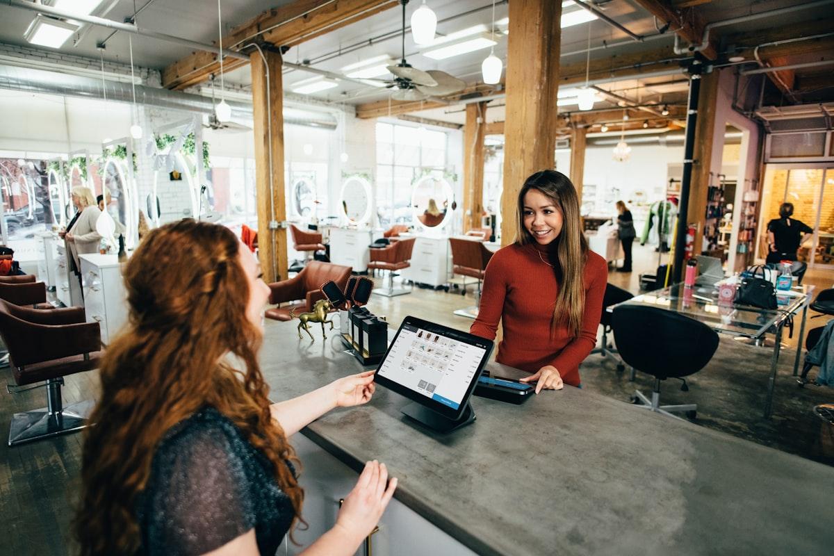 Retail staff member smiling while helping a customer at a modern checkout counter with tablet POS